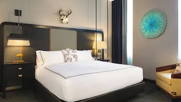 A hotel room with a large bed, two bedside lamps, a decorative wall piece, and a chair.