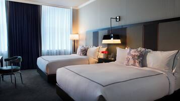 A hotel room with two beds, a desk, and a chair.