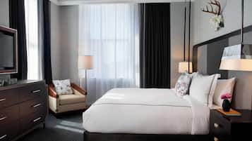 Une chambre d’hôtel avec un grand lit, un bureau, une chaise, une télévision et une fenêtre avec des rideaux.