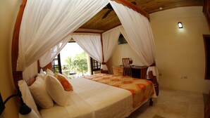A bedroom with a four-poster bed, a desk, and a chair.
