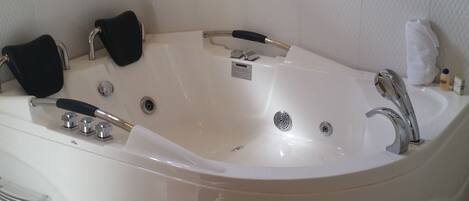 A modern bathroom with a freestanding bathtub, a handheld showerhead, and a built-in toilet.