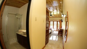 A bathroom with a glass shower enclosure, a sink, and wooden cabinets.