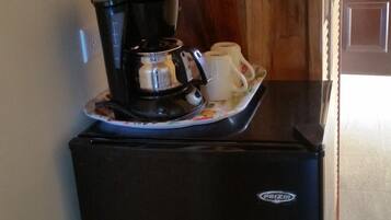 Un refrigerador negro compacto con una cafetera y una taza encima.