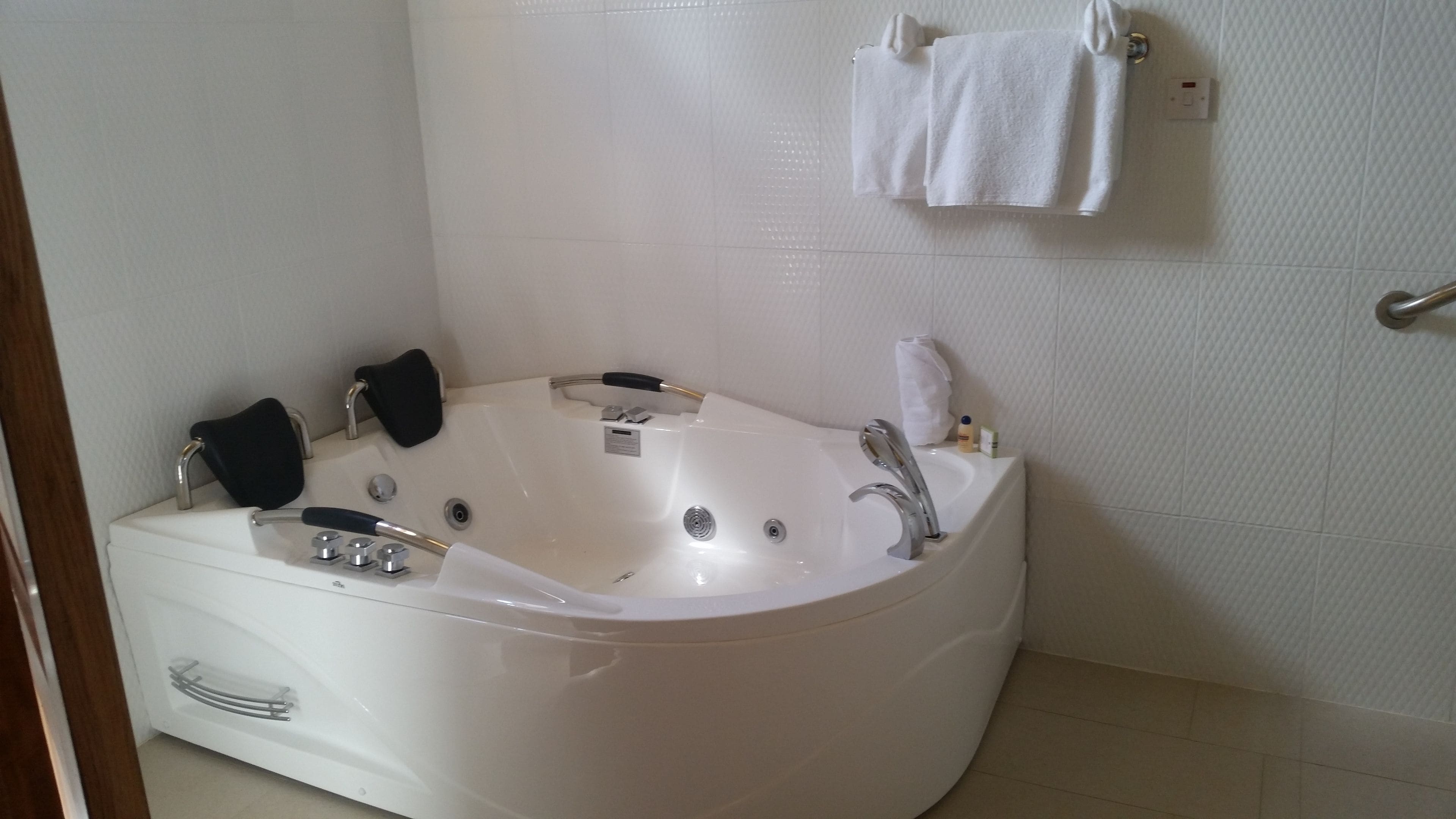 A modern bathroom with a large freestanding bathtub, a handheld showerhead, and a wall-mounted towel rack.