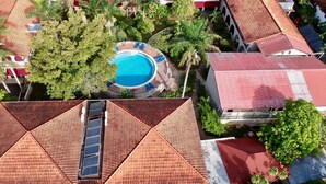 An aerial view of a resort with a swimming pool surrounded by palm trees and a beach.