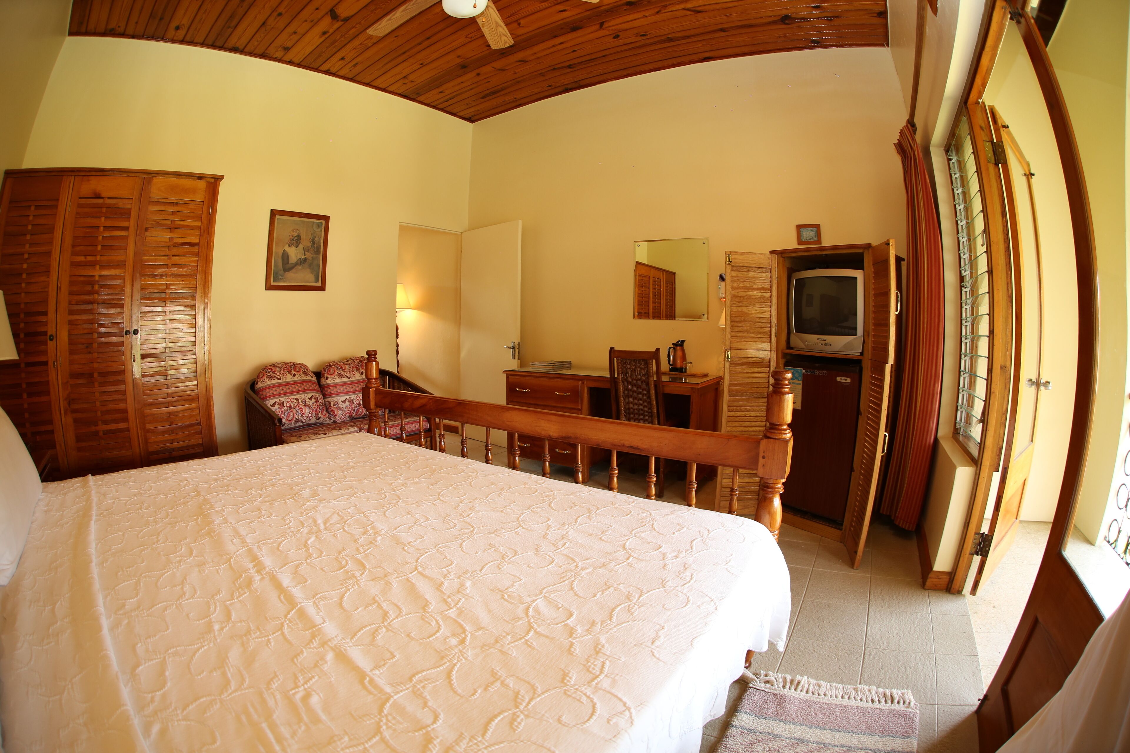 Un dormitorio con una cama grande, muebles de madera, una televisión y un espejo.