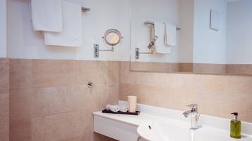 Un baño moderno con un lavamanos blanco, un espejo y un perchero para toallas.