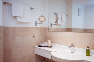 Un baño moderno con un lavamanos blanco, un espejo y un perchero para toallas.