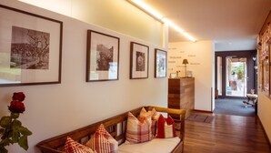 A reception area with a wooden bench, framed pictures on the wall, and a welcome sign. - Hotel Restaurant Weinstube (Eschen)
