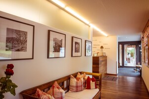 Un área de recepción con un banco de madera, cuadros en la pared y un letrero de bienvenida.