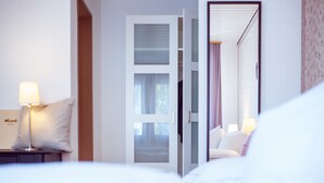 A hotel room with a bed, a nightstand with a lamp, and an open door leading to another room. - Hotel Restaurant Weinstube (Eschen)