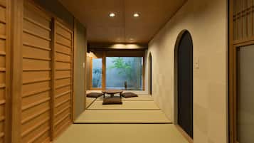 A traditional Japanese interior with tatami flooring, a low table with cushions, and sliding doors.