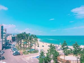 A coastal cityscape with a beach, parked cars, and buildings. - GN Guesthouse Coffeemarina - Hostel (Gangneung)