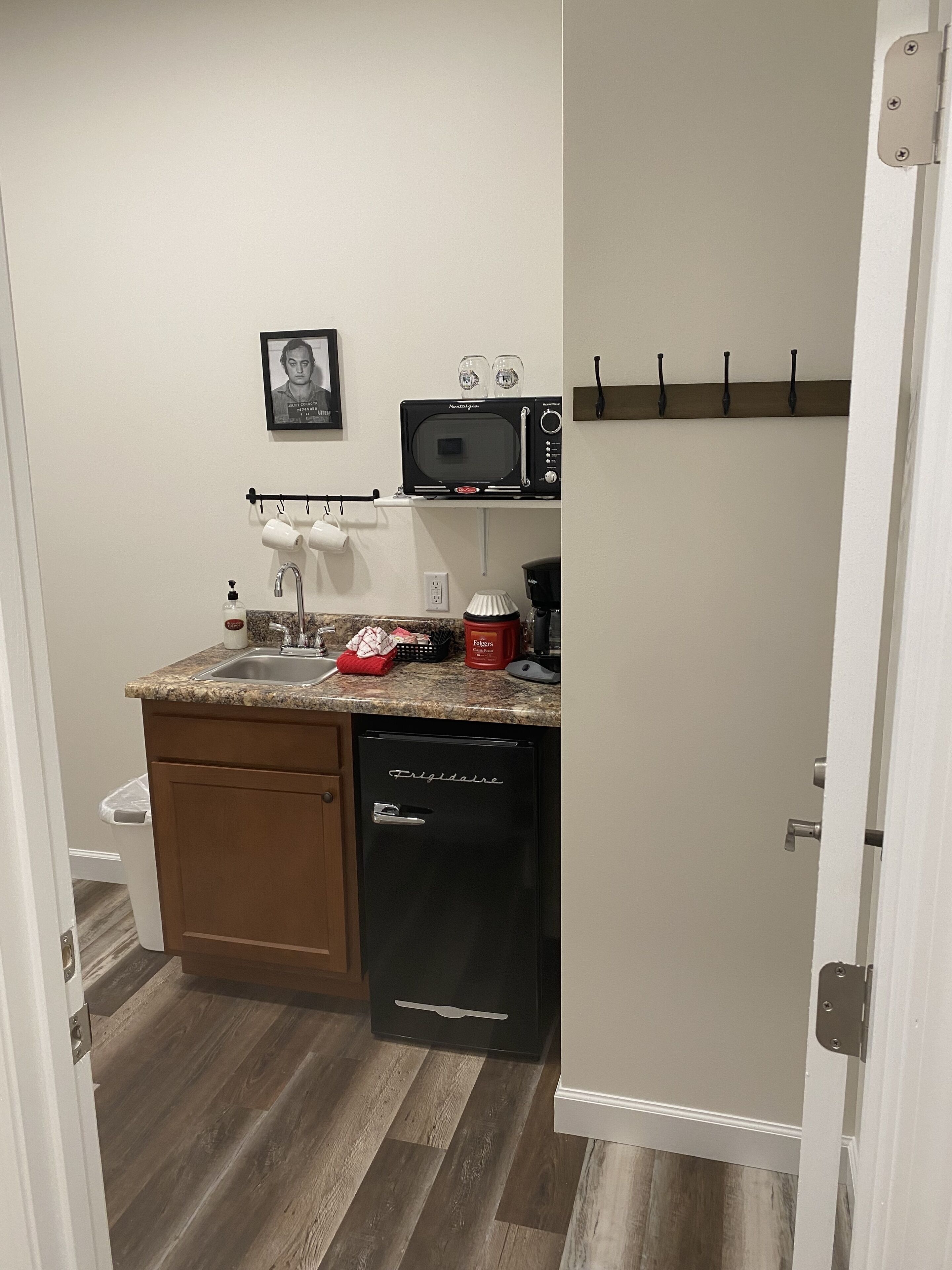 A compact kitchen with a built-in microwave, a coffee maker, and a small trash bin.