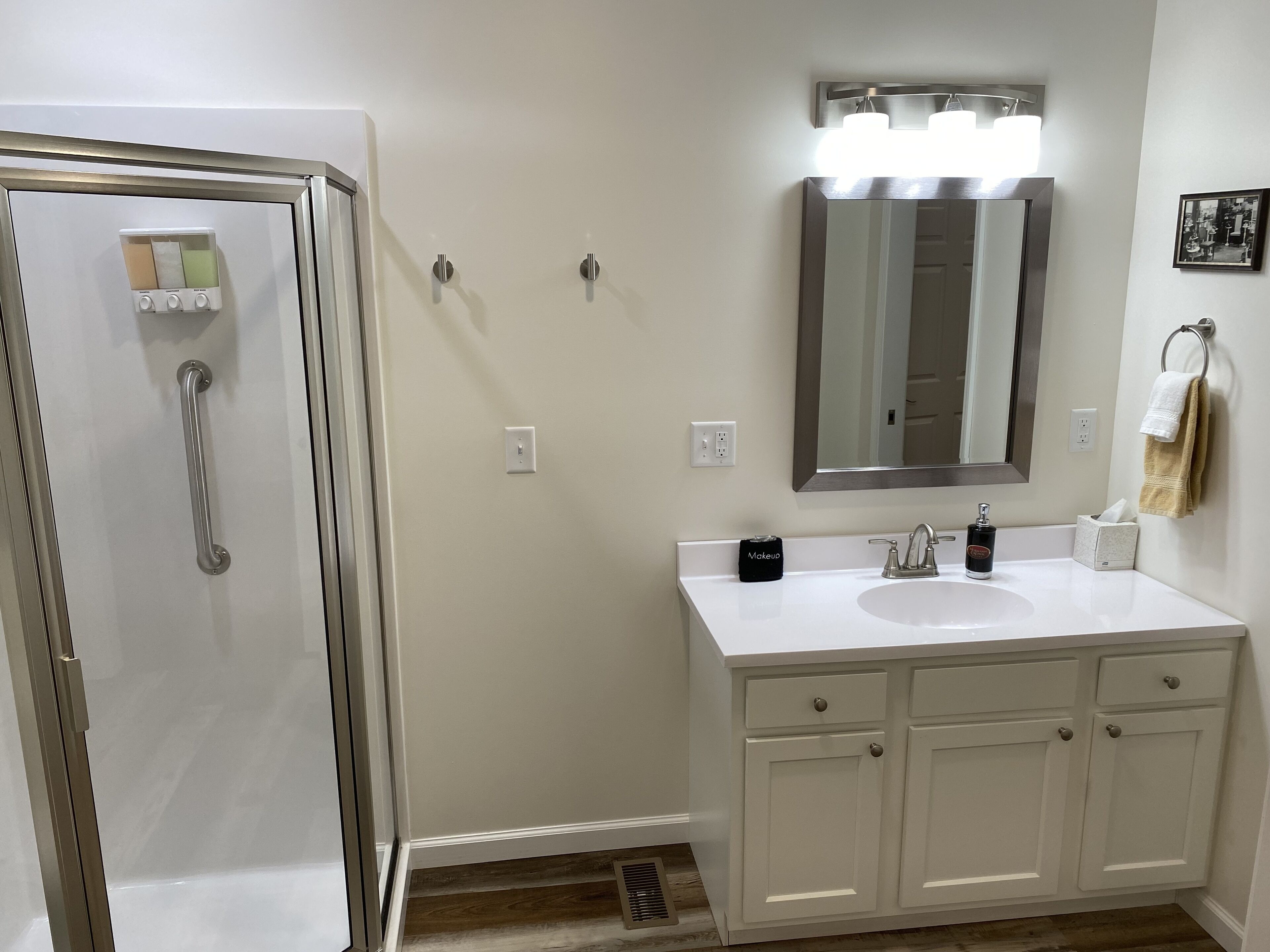 A bathroom with a shower, a sink, a mirror, and a towel rack.