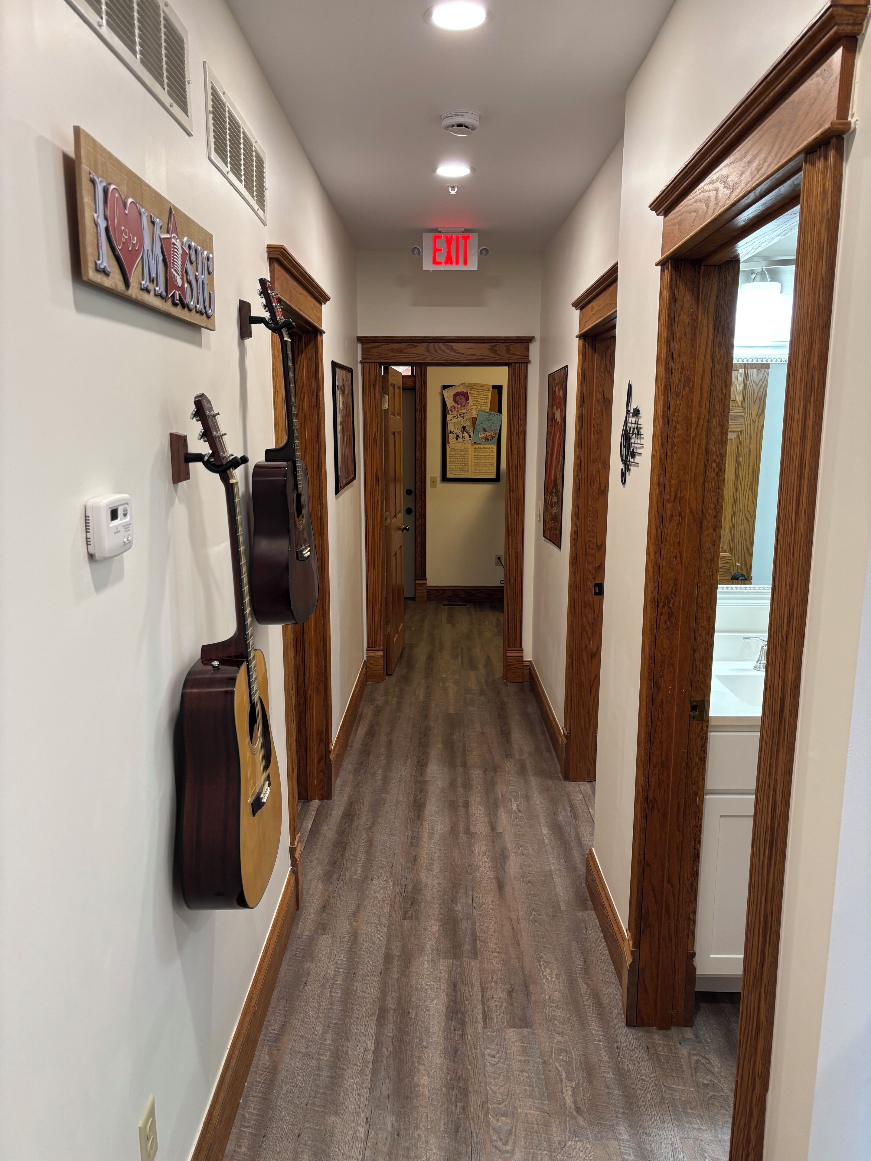 A hallway with wooden doors, a guitar, and a sign that says "EXIT".