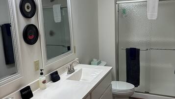 A modern bathroom with dual sinks, a large mirror, and a glass-enclosed shower.