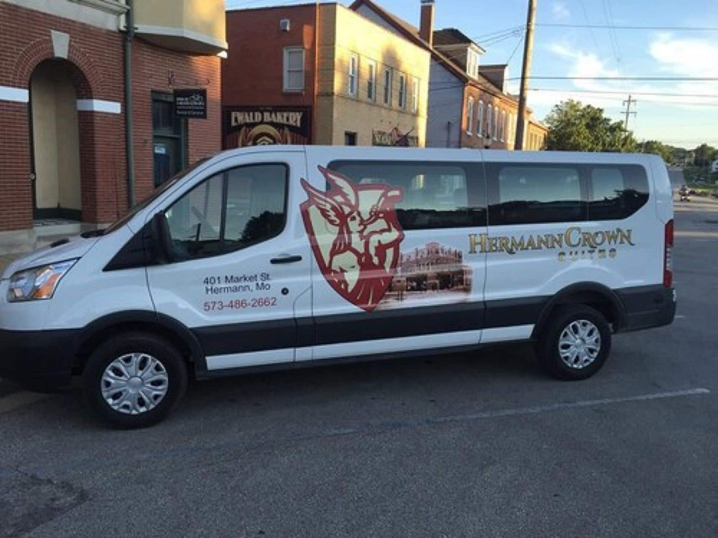 A white van parked on a street with a logo and contact information on the side.