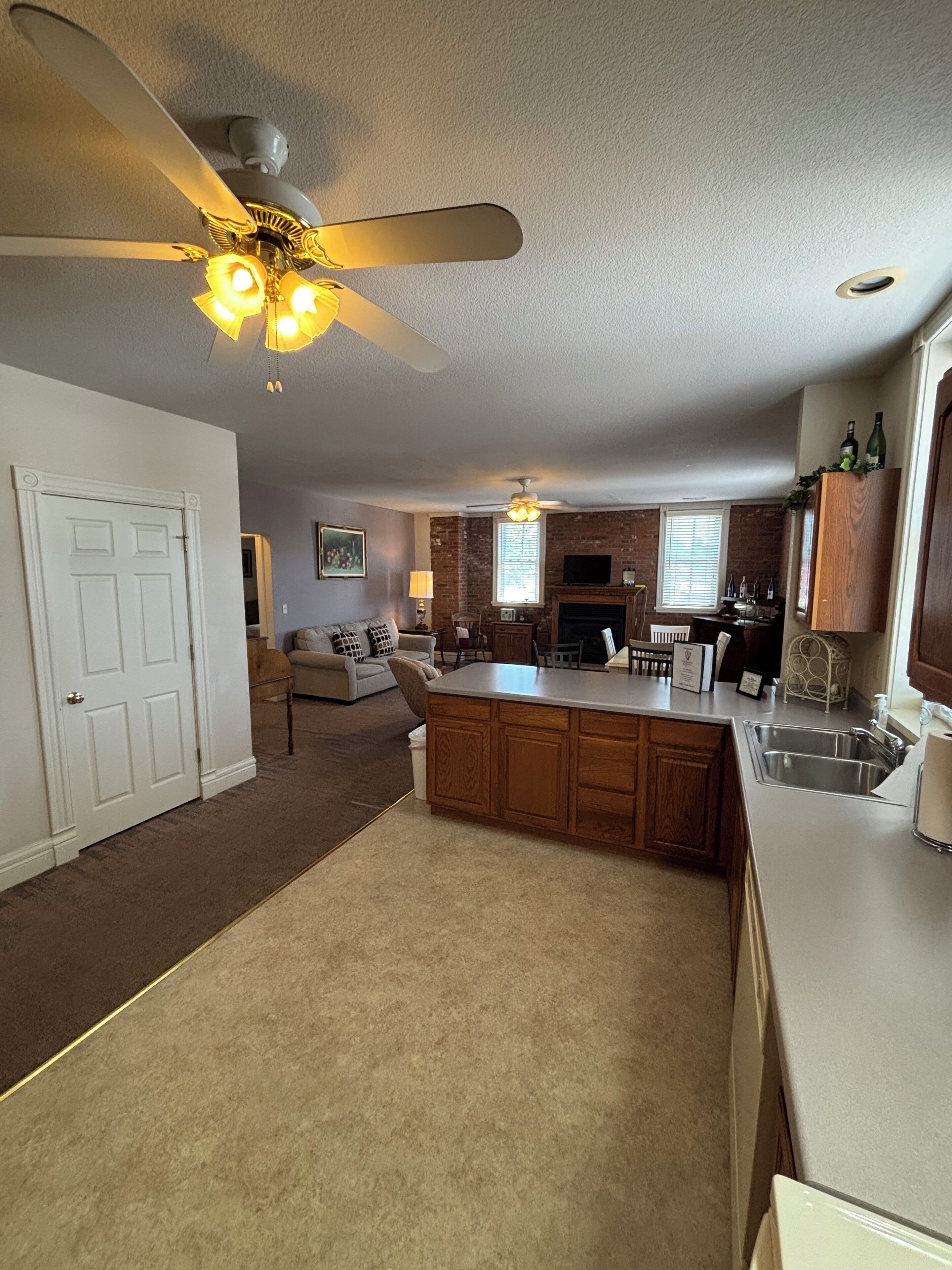 A kitchen with a central island, a ceiling fan, and a fireplace.