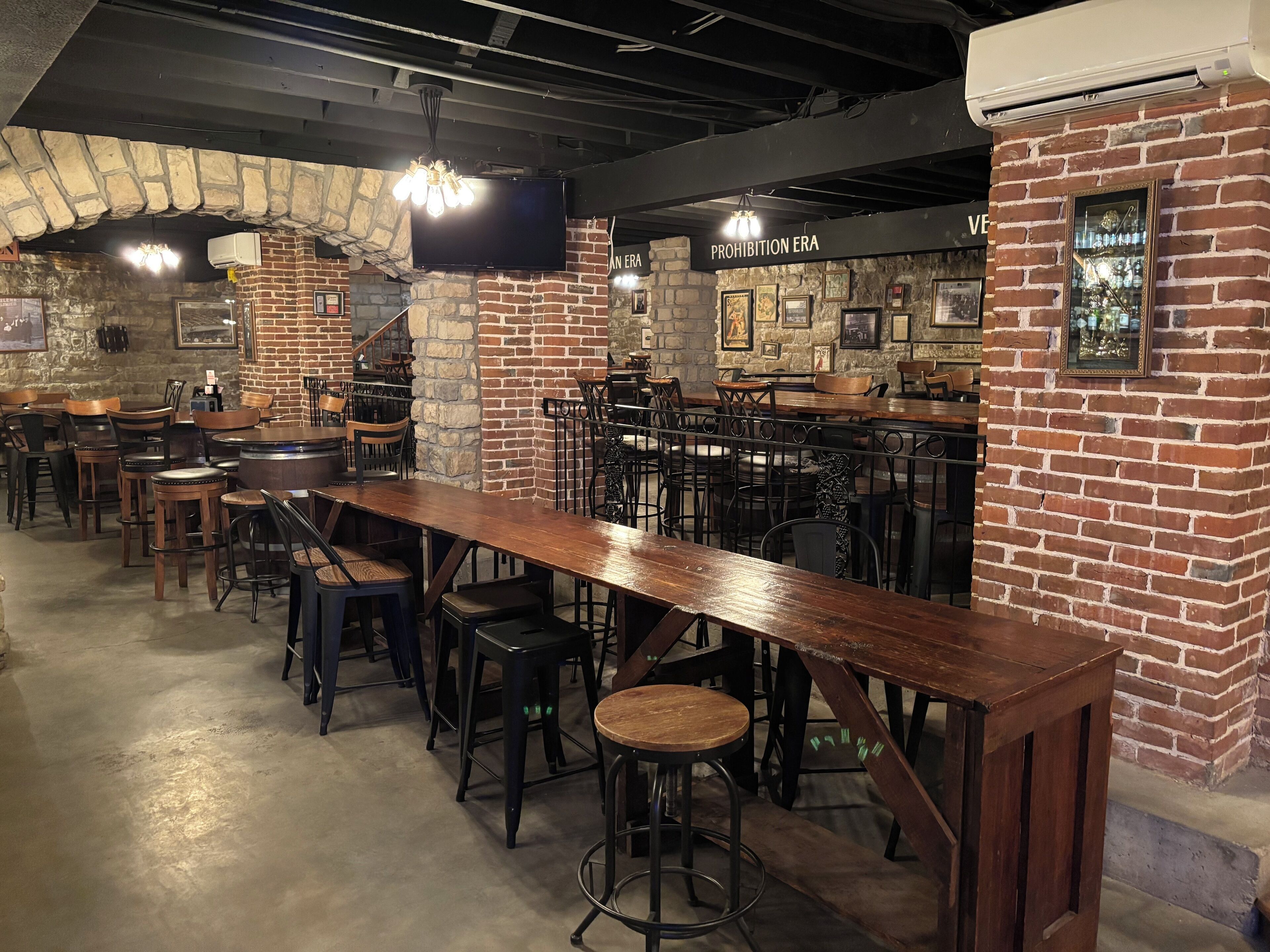Un restaurant aux murs de briques, aux tables en bois et aux tabourets de bar.