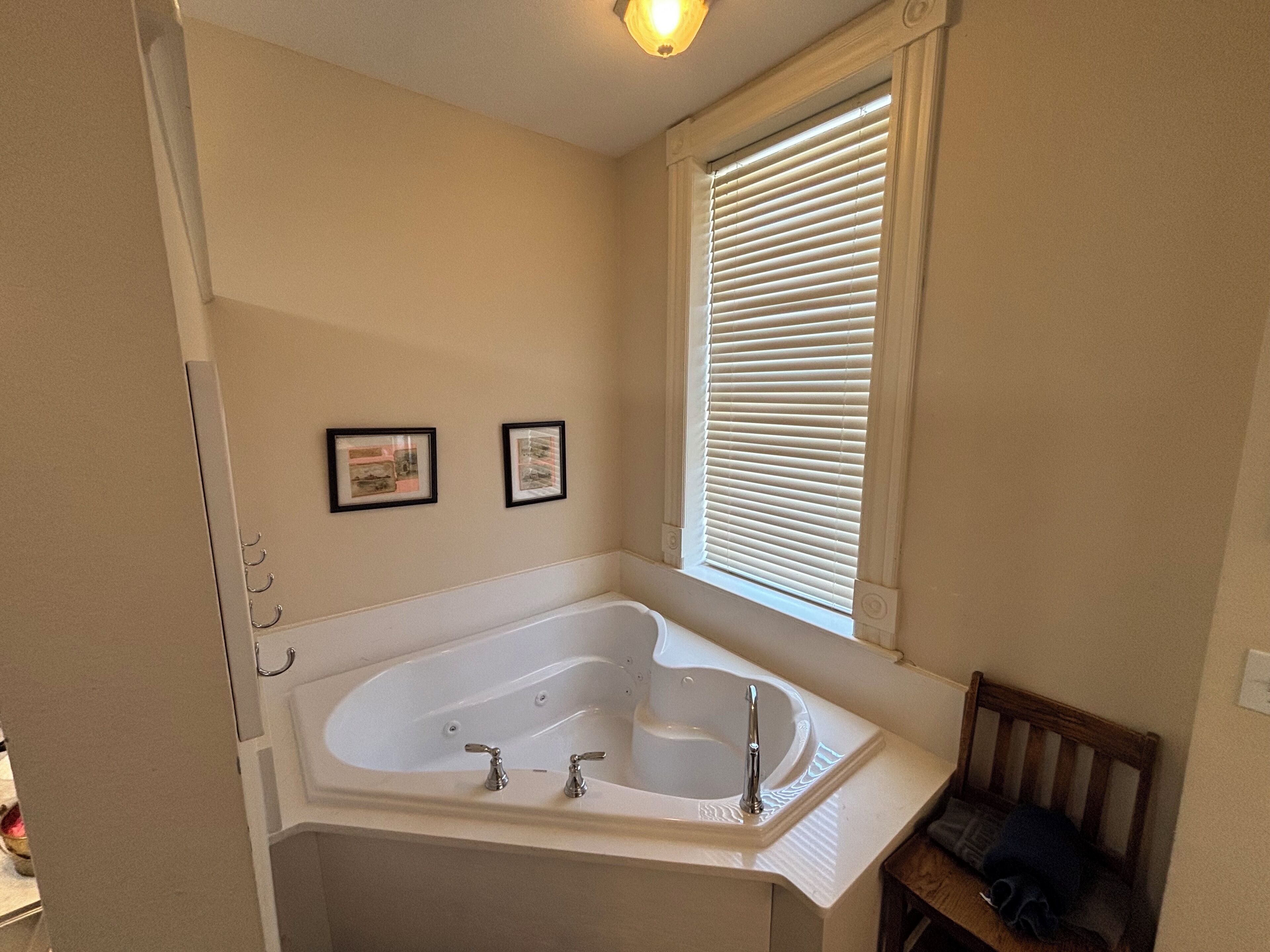 A bathroom with a freestanding bathtub, a wooden bench, and two framed pictures on the wall.