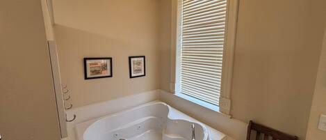 A bathroom with a freestanding bathtub, a wooden bench, and two framed pictures on the wall.