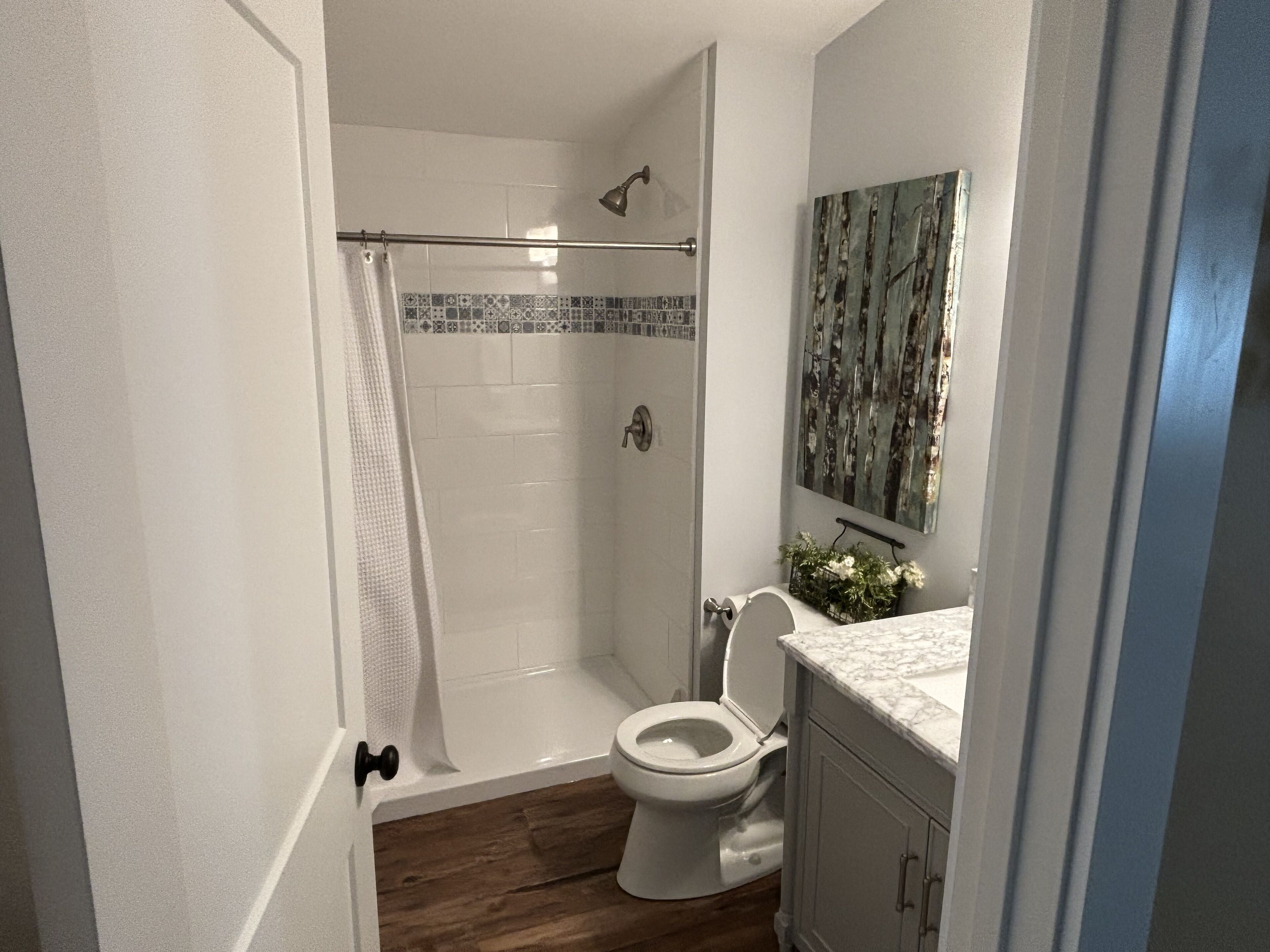 Un baño con ducha, inodoro y lavabo con espejo.