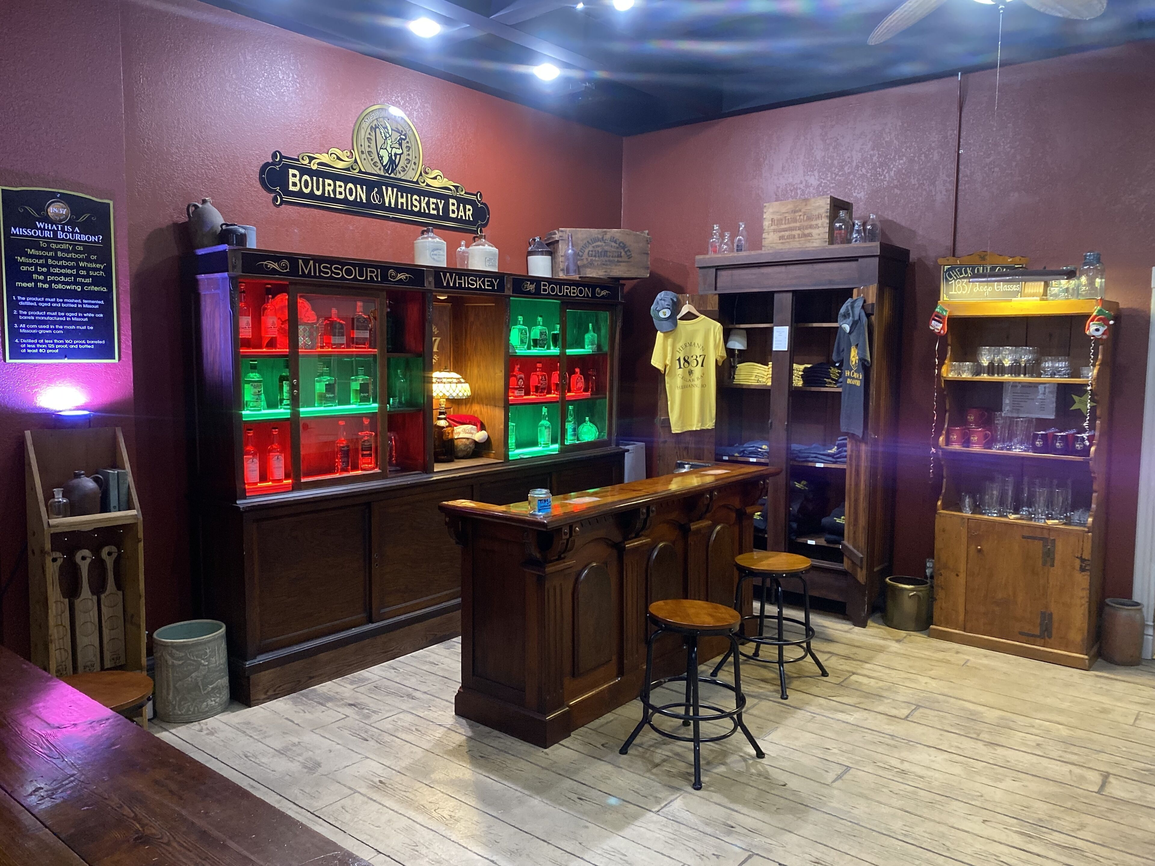 A bar with wooden bar stools, shelves of liquor, and a sign reading "Bourbon & Whiskey Bar".