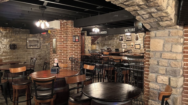 A restaurant with brick walls, wooden tables, and chairs. - Hermann Crown Suites (Hermann)