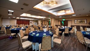 Une salle de conférence équipée de tables rondes, de chaises et d’un lustre.