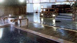 A traditional Japanese onsen with wooden benches, a stone wall, and a wooden staircase leading to a hot spring area. - Kinugawa Park Hotels (Nikko)