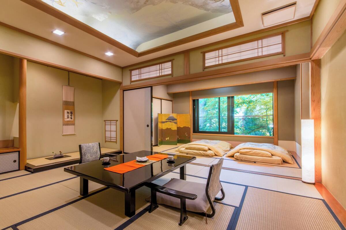 Una habitación tradicional japonesa con suelo de tatami, una mesa baja y una cama futón.