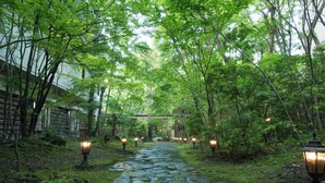 A stone pathway in a lush garden with lanterns. - Kinugawa Park Hotels (Nikko)