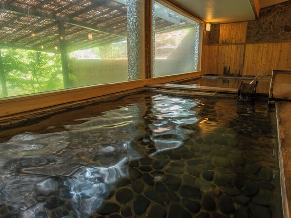 A stone hot tub with a view of trees through a window. - Kinugawa Park Hotels (Nikko)