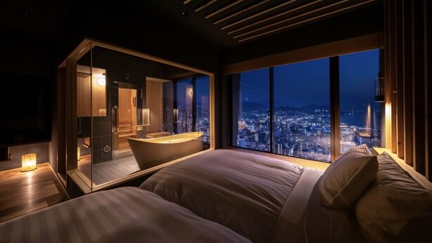 Ein modernes Hotelzimmer mit Stadtblick, einem separaten Badezimmer und einer gemütlichen Sitzecke.