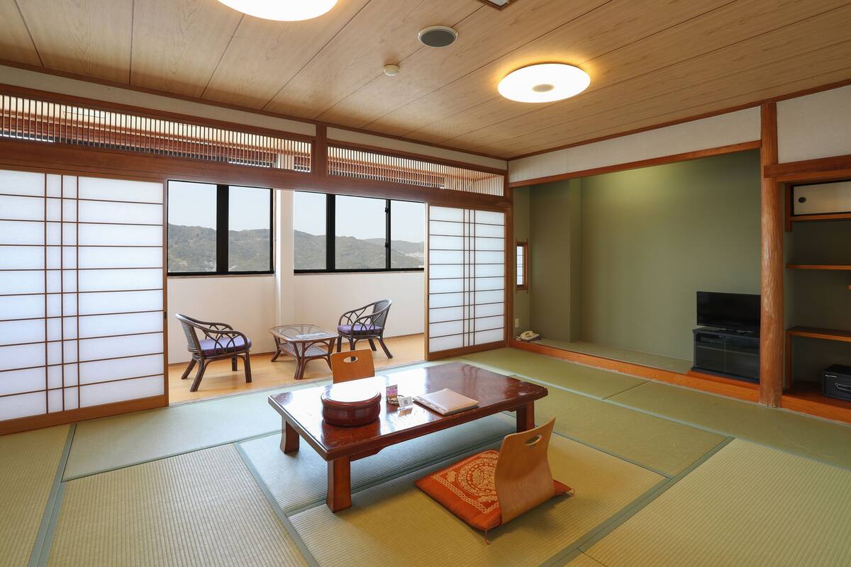 Una habitación japonesa tradicional con suelo de tatami, una mesa de madera baja y un panel corredero shoji.