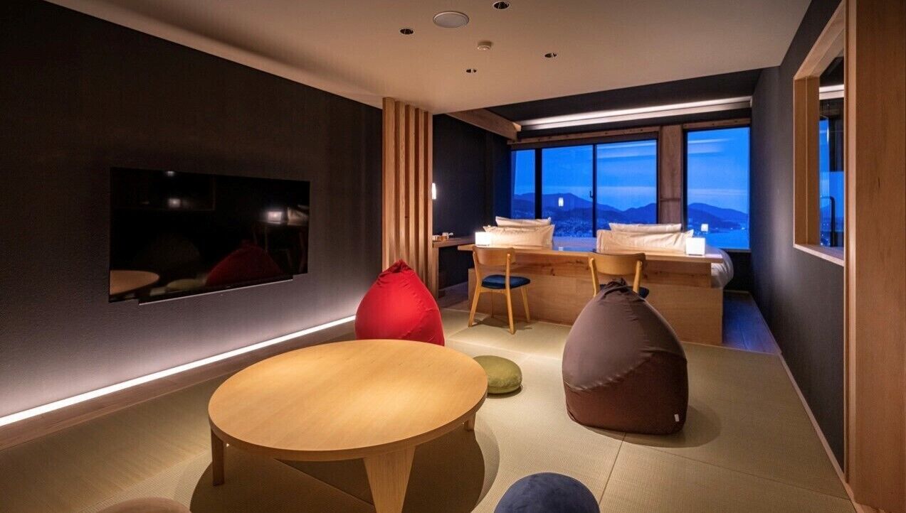 Ein modernes Zimmer mit einem Bett, einem runden Tisch und Sitzsäcken.