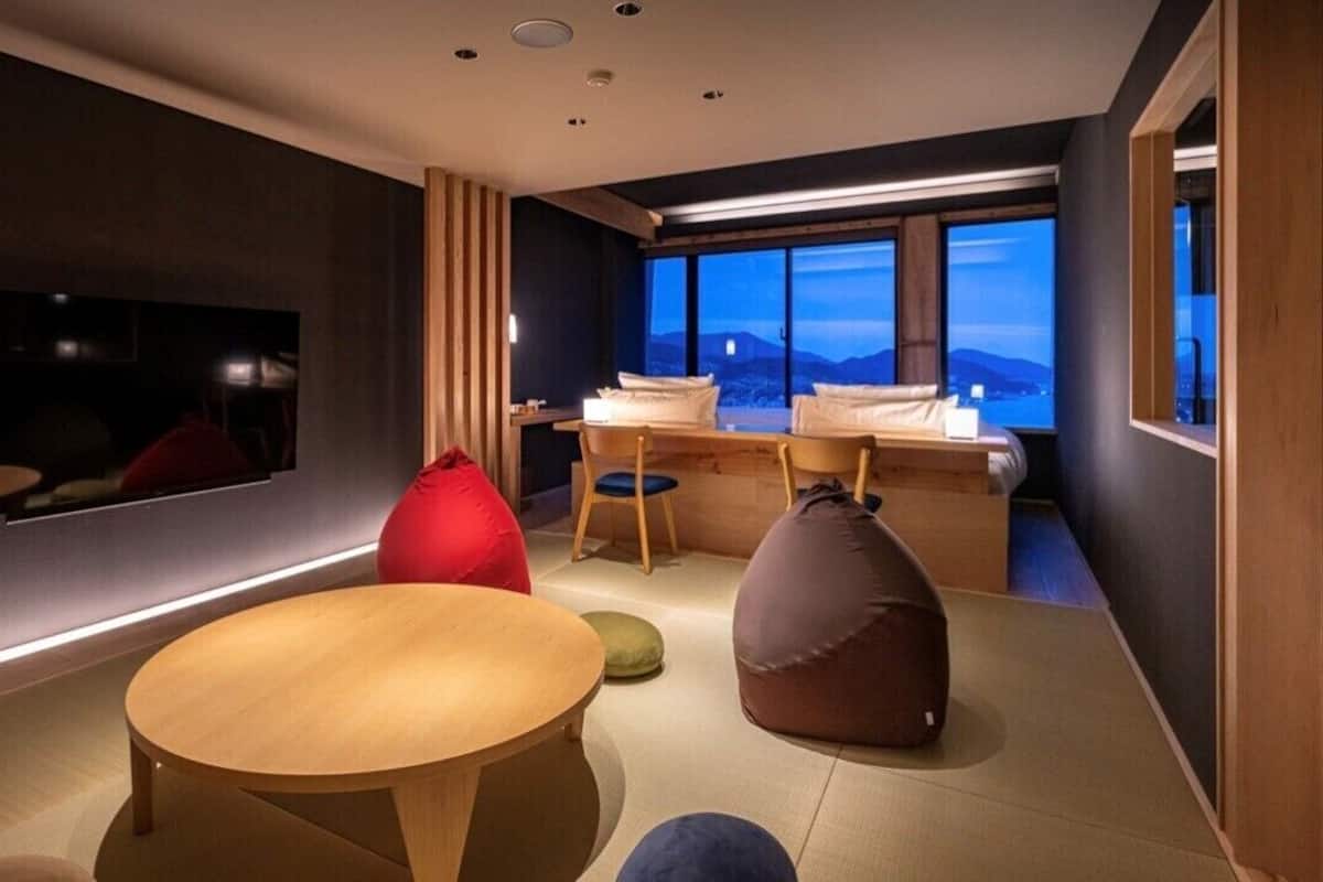 Una habitación moderna con una cama, una mesa redonda y sillones informales.