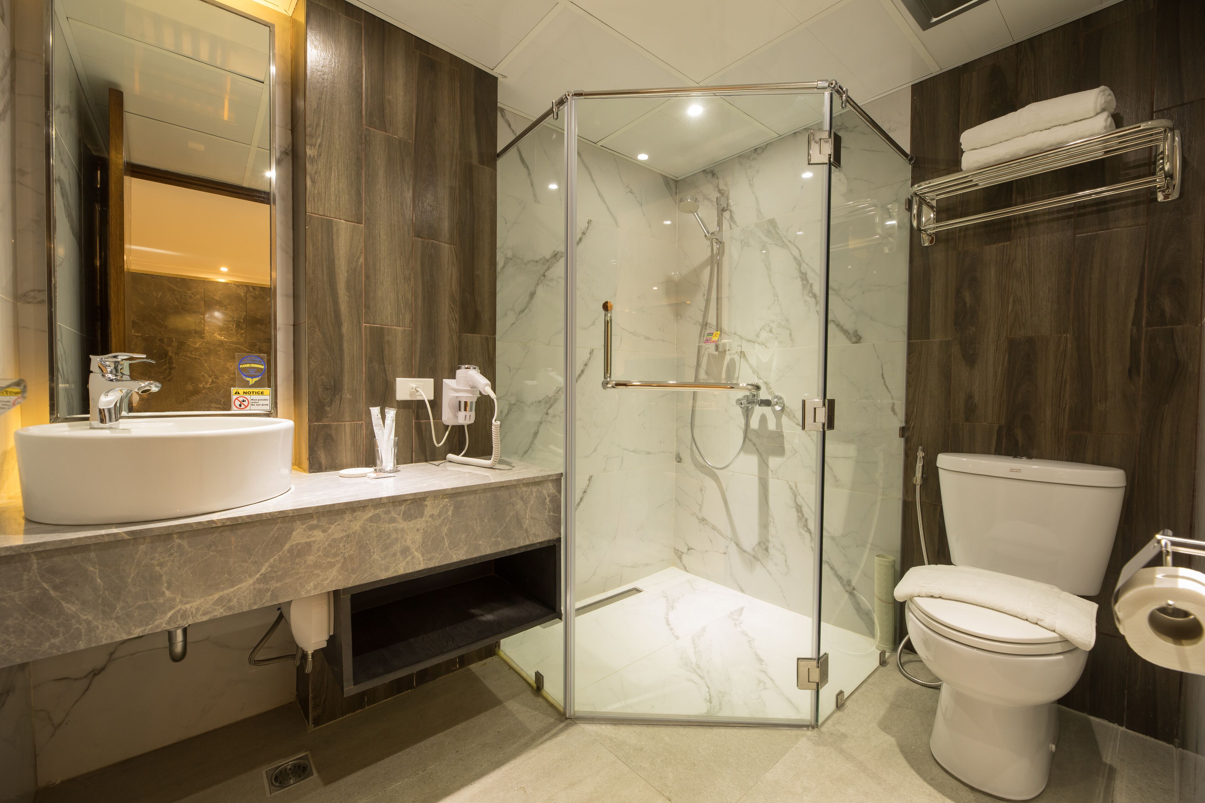 A modern bathroom with a glass-enclosed shower, a white sink, and a toilet.