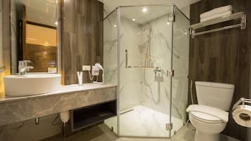A modern bathroom with a glass-enclosed shower, a white sink, and a toilet.