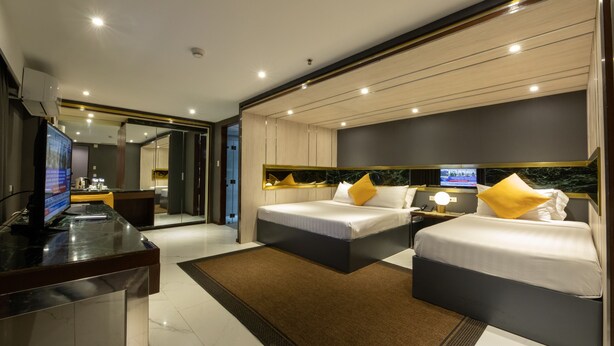Una habitación de hotel moderna con dos camas, un escritorio con computadora y televisión.