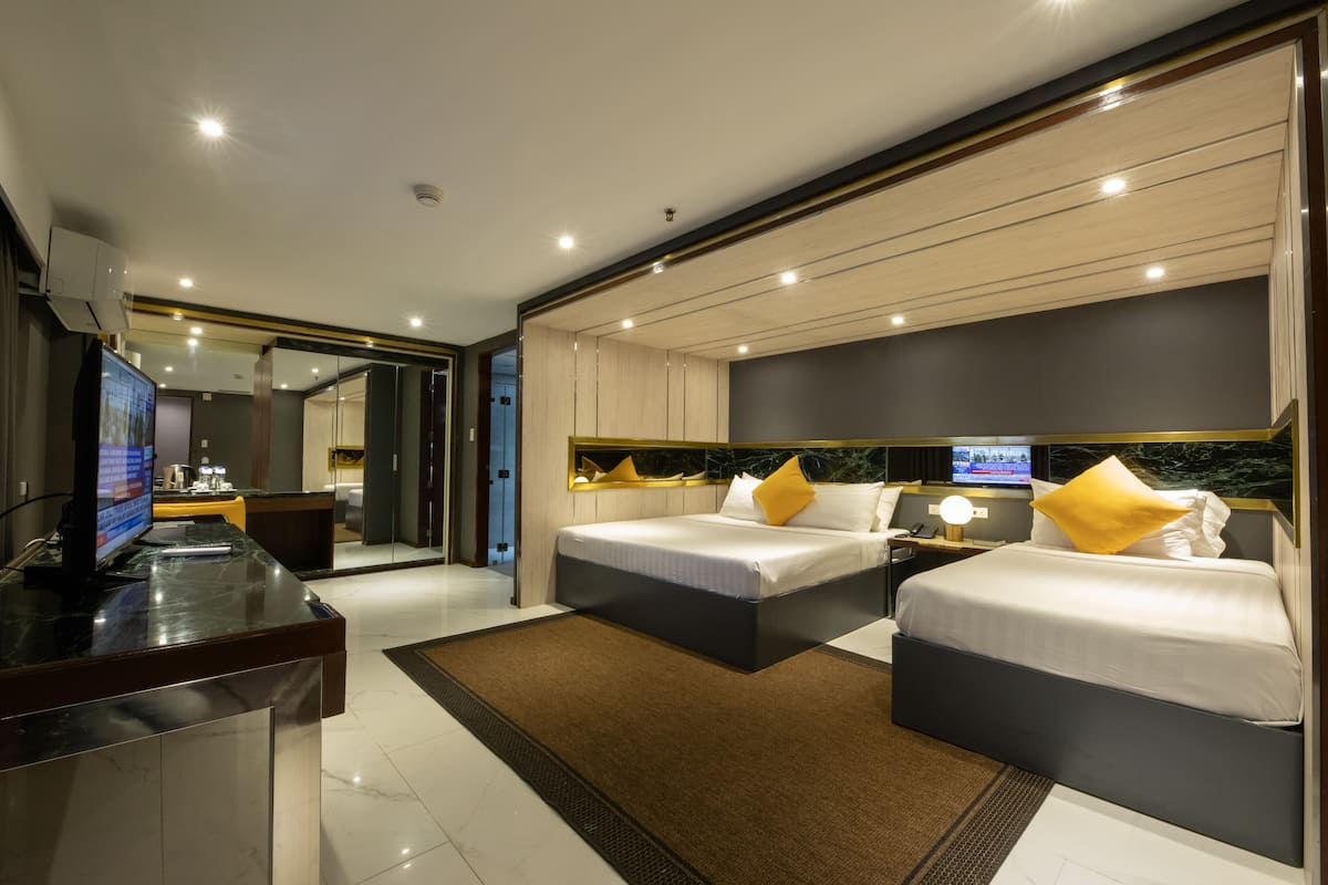 Una habitación de hotel moderna con dos camas, un escritorio con computadora y televisión.