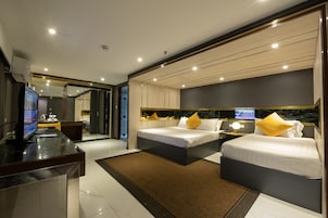 Quarto de hotel moderno com duas camas, uma escrivaninha com computador e televisão.