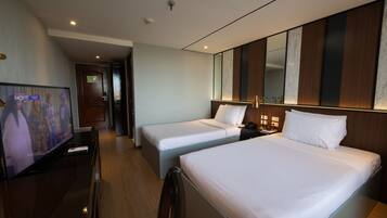 A hotel room with two beds, a TV, and a wooden headboard.