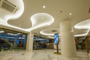 Um lobby moderno com teto curvo, balcão de recepção e painel informativo digital.