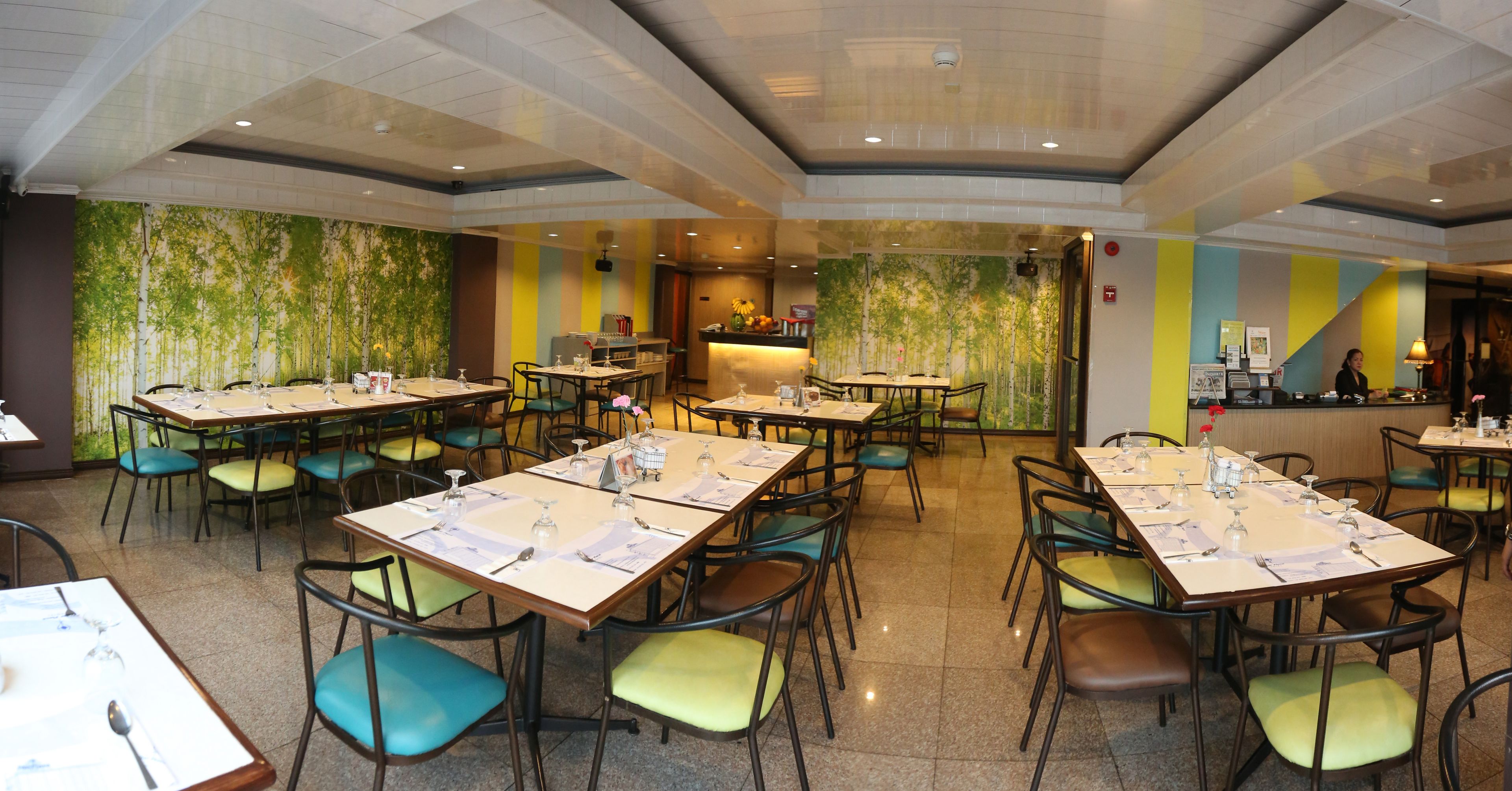 Un restaurante amplio con varias mesas y sillas, una zona de bar y un mural en la pared.
