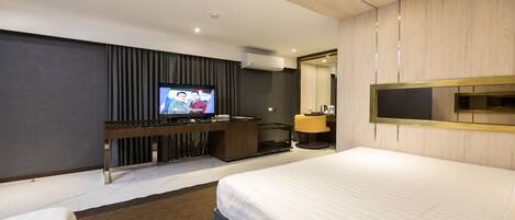 Una habitación de hotel moderna con una cama grande, un televisor de pantalla plana, un escritorio con una computadora y un espejo.