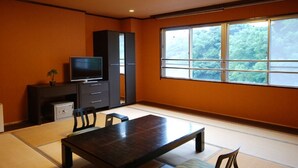A traditional Japanese room with tatami flooring, a low table, and a television on a cabinet. - Nagasaki Sky Hotel (Nagasaki)