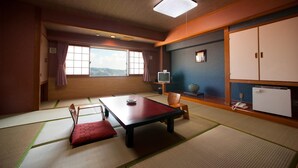 A traditional Japanese room with tatami flooring, a low table, a television, and a wardrobe. - Nagasaki Sky Hotel (Nagasaki)