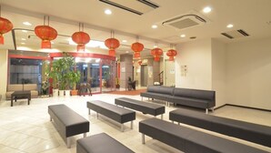 A lobby with black benches, red lanterns, and a reception desk. - Nagasaki Sky Hotel (Nagasaki)